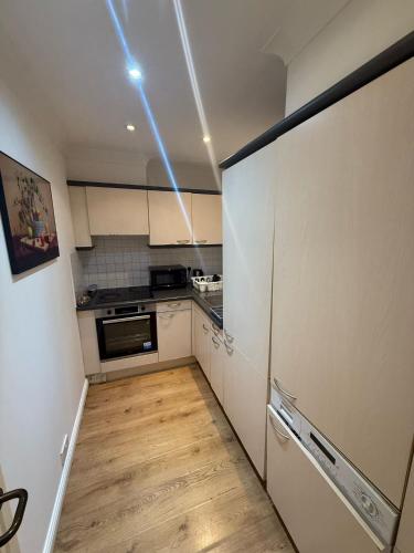 a kitchen with white cabinets and a wooden floor at 1 Bedroom Apartment with security 24 hours and concierge in London