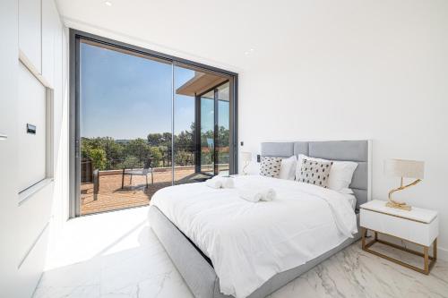 une chambre avec un lit blanc et une grande fenêtre dans l'établissement VILLA PIBONSON - Villa d Exception a Mougins - Luxe, Piscine et Spa, à Mougins