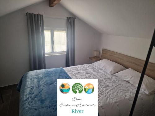 a room with a bed with a sign on it at Carbonças River Apartments in Ribeiros