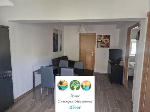 a living room with a table and chairs and a sign at Carbonças River Apartments in Ribeiros