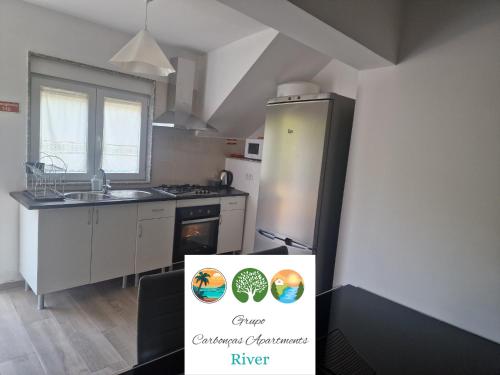 a kitchen with a refrigerator and a sign in front of it at Carbonças River Apartments in Ribeiros