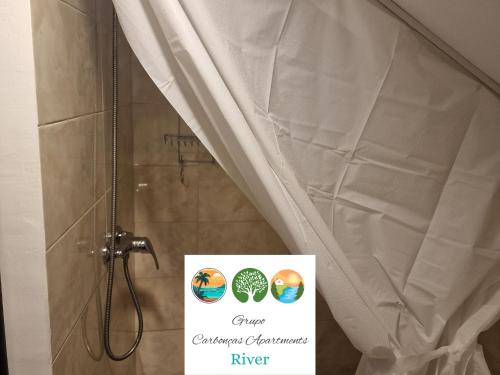 a sign in a shower with a shower curtain at Carbonças River Apartments in Ribeiros