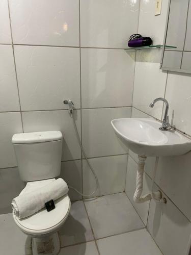 a white bathroom with a toilet and a sink at Villa Noronha Hostel e Suites in Fernando de Noronha