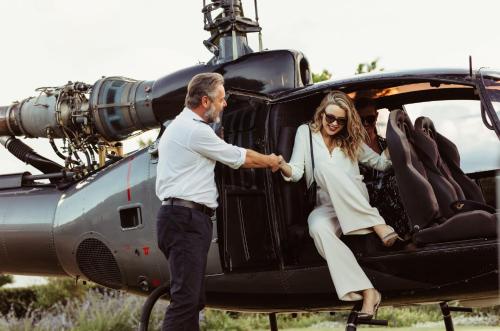 a man helping a woman get out of a helicopter at White Cocoon Exclusive villas in Naxos Chora