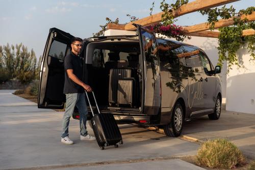 a man pulling a suitcase out of a van at White Cocoon Exclusive villas in Naxos Chora