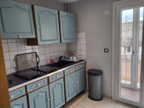 une cuisine avec des armoires bleues, un évier et une fenêtre dans l'établissement Appartement 3 pièces proche de la mer et centre avec parking privatif, à Valras-Plage