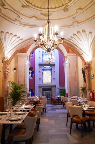 a dining room with tables and chairs and a chandelier at Casa Postal Hotel Boutique in Querétaro