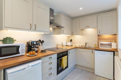 a kitchen with white cabinets and a microwave at AIRE VUE - Skipton in Skipton