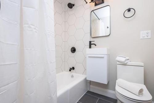a white bathroom with a toilet and a mirror at Newly Renovated w Exposed Brick in Boston
