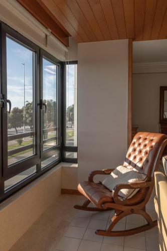 a rocking chair in a room with windows at Vista Atlântica-Vila do Conde in Vila do Conde