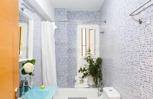 La salle de bains est pourvue de carrelage bleu, d'une baignoire et d'un lavabo. dans l'établissement Placentines, à Séville
