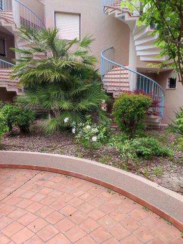 une passerelle en briques devant un bâtiment avec des plantes dans l'établissement Le Palmier, jardin privatif, plage 200m, classé 3 étoiles, wifi, garage,rénové en 2024, à Cavalaire-sur-Mer