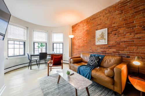 a living room with a couch and a brick wall at Bright and Cozy Studio Apartment in Boston
