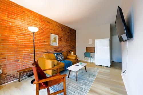 a living room with a couch and a brick wall at Bright and Cozy Studio Apartment in Boston