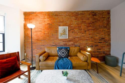 a living room with a couch and a brick wall at Bright and Cozy Studio Apartment in Boston