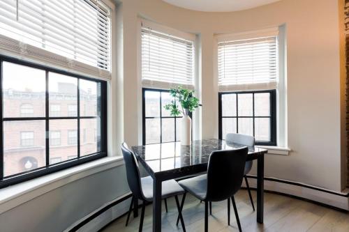 a dining room with windows and a table and chairs at Bright and Cozy Studio Apartment in Boston
