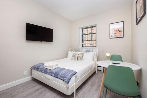 a bedroom with a bed and a table and a tv at Compact Back Bay Studio in Boston