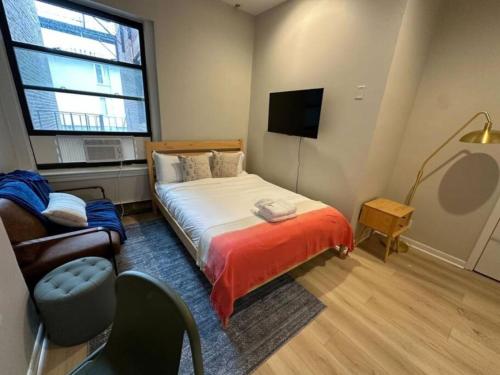 a bedroom with a bed and a couch and a television at Airy Studio South End in Boston