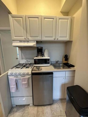a kitchen with white cabinets and a stove and a sink at Airy Studio South End in Boston