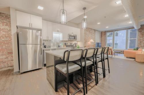 a kitchen with a bar with chairs and a refrigerator at Downton Boston Luxurious 2 Bed in Boston