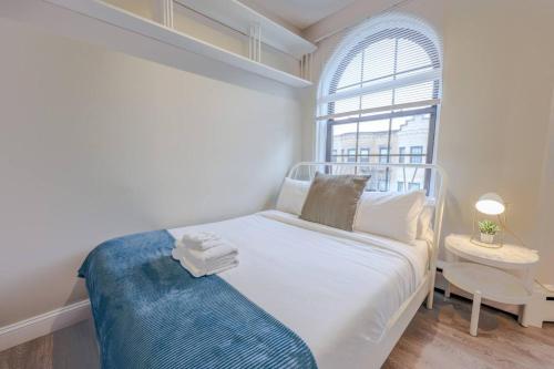 a small bedroom with a white bed and a window at Spacious Studio Apt South End in Boston