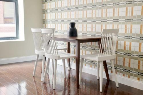 a wooden table with three chairs and a vase on it at Lux 2br in the Heart of FIDI in Boston
