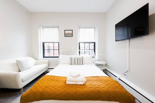 a white bedroom with a bed and a couch at Modern Bright Back Bay Studio in Boston
