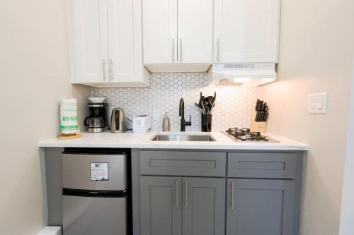 a kitchen with white cabinets and a sink and a dishwasher at Modern Bright Back Bay Studio in Boston
