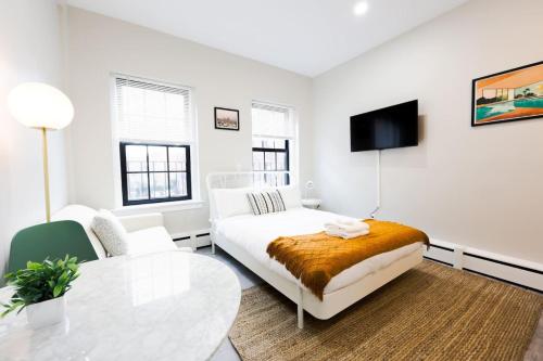 a white living room with a couch and a table at Modern Bright Back Bay Studio in Boston