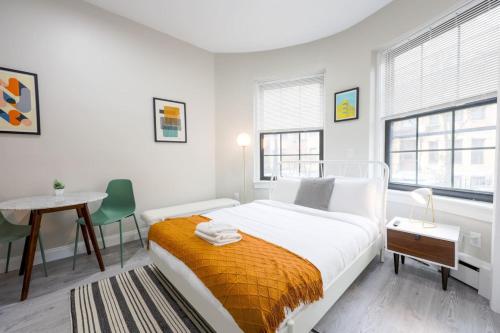 a white bedroom with a bed and a table at Vibrant Studio in Prudential Area in Boston