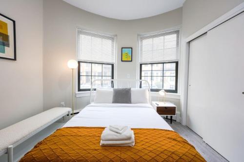 a white bedroom with a bed and two windows at Vibrant Studio in Prudential Area in Boston