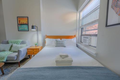 a bedroom with a bed and a chair and a window at Modern South End Studio Apt in Boston