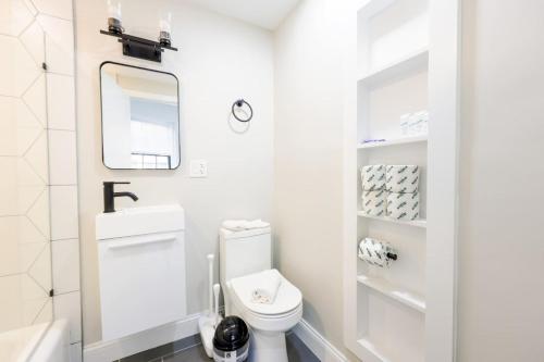 a white bathroom with a toilet and a mirror at Vibrant Studio in Prudential Area in Boston