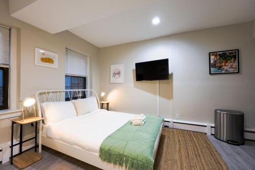 a bedroom with a white bed and a flat screen tv at Studio Nestled in Back Bay in Boston