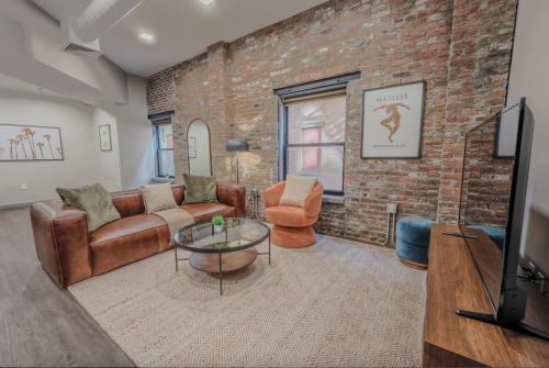 a living room with leather furniture and a brick wall at Charming 1 Bedroom Apt Laundry in Unit in Boston