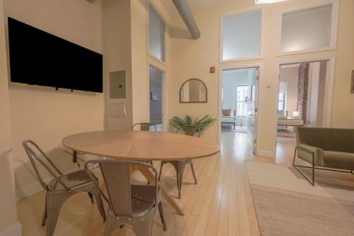 a living room with a table and chairs and a tv at Stylish Exposed Brick 3 Bedroom in Boston