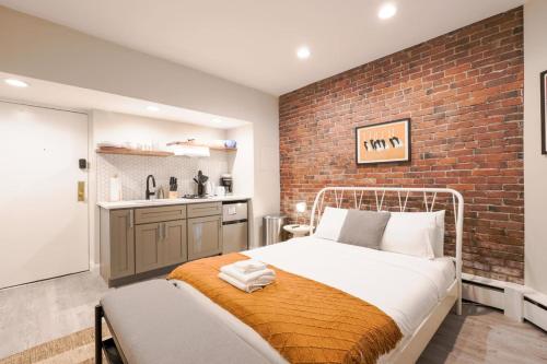Un dormitorio con una pared de ladrillo y una cama. en Cozy Garden Level Studio, en Boston