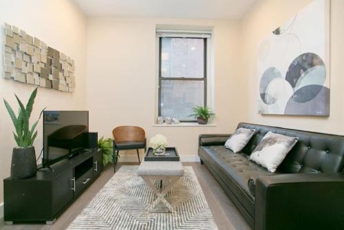 a living room with a black leather couch and a tv at Newly Designed Loft - Fast Wifi - Pet Friendly in Boston