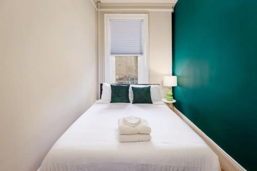 a bedroom with a white bed with a green wall at Beautiful Newbury St 1 Bedroom unit in Boston