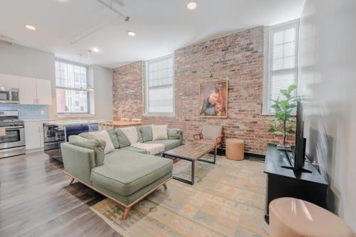a living room with a couch and a brick wall at Lavishly Designed Home With Office Close to T in Boston