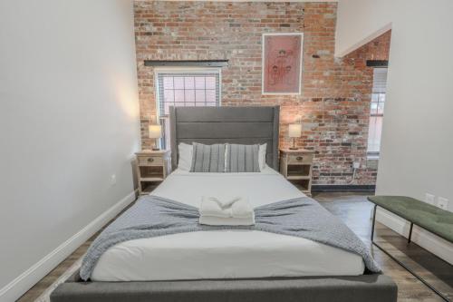 a large bed in a room with a brick wall at Lavishly Designed Home With Office Close to T in Boston