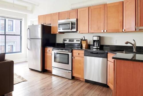 a kitchen with stainless steel appliances and wooden cabinets at Cozy 2 Bed in Boston FIDI District in Boston