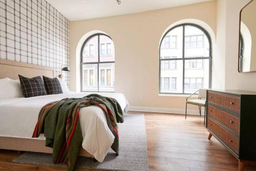 a bedroom with a bed with two windows and a dresser at Spacious 2br FIDI District Centrally Located in Boston
