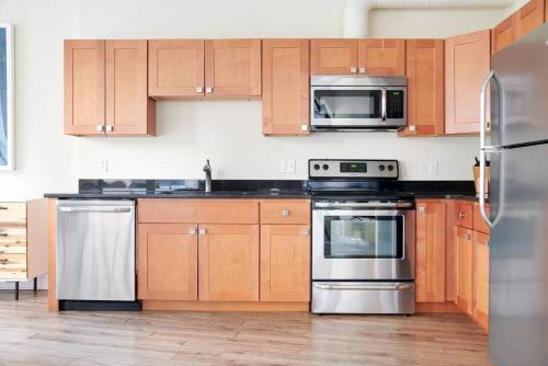 a kitchen with wooden cabinets and stainless steel appliances at Spacious 2br FIDI District Centrally Located in Boston