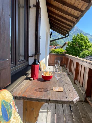 a wooden table with two wine glasses on a balcony at Haus KaiserInn - komfortable Wohnung 82 qm TOP ausgestattet, 2 Schlafzimmer mit Balkon und Bergblick in Flintsbach