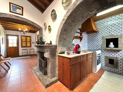 a kitchen with a stone fireplace in a room at Sete Cidades House in Sete Cidades