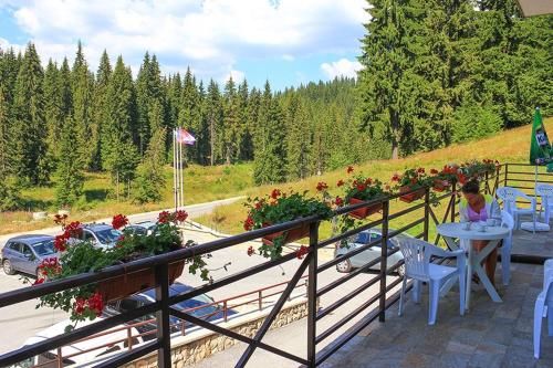 a woman sitting at a table on a balcony with flowers at Alpine Relax free spa & pool in Pamporovo