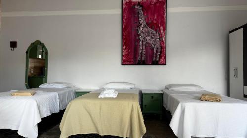 a room with three beds and a picture on the wall at Pousada Minha Casa- Aconchegante no Centro de São Lourenço in São Lourenço