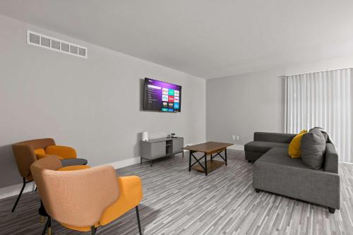 a living room with a couch and chairs and a tv at Perfect Getaway Comfort & Stunning City Views in Rochester Hills