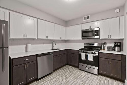 a kitchen with white cabinets and stainless steel appliances at Perfect Getaway Comfort & Stunning City Views in Rochester Hills